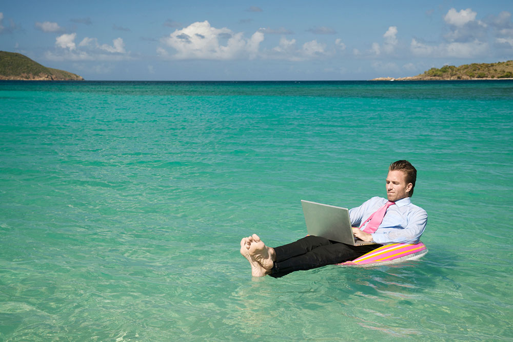 Remote worker floating in the sea with laptop