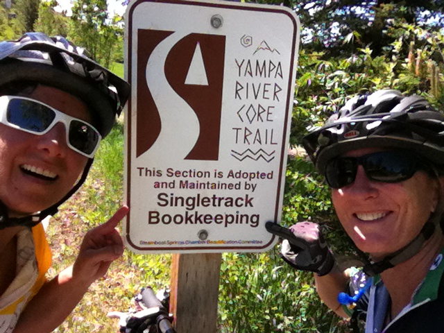 Singletrack Bookkeeping owners pointing at a sign on the Yampa River Core Trail