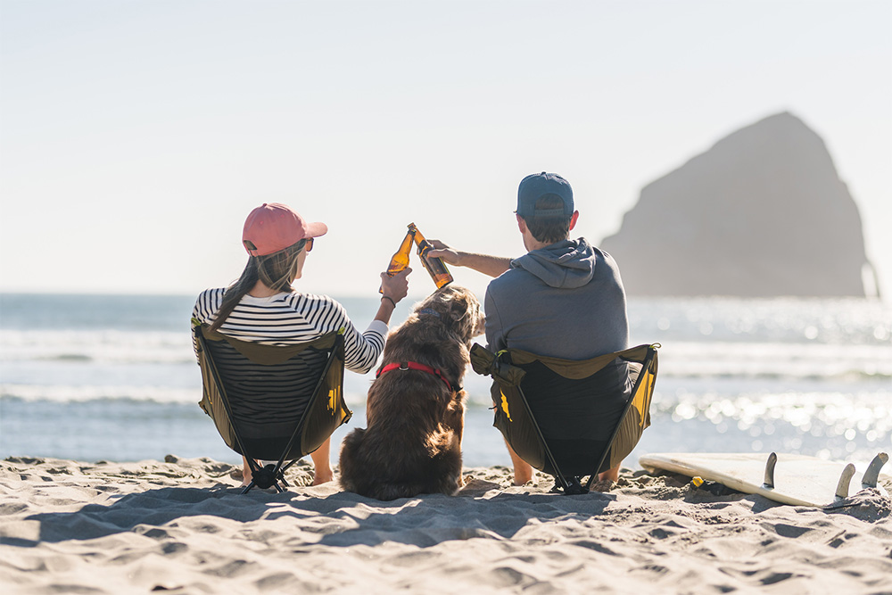 couple drinking on the beach with their dog